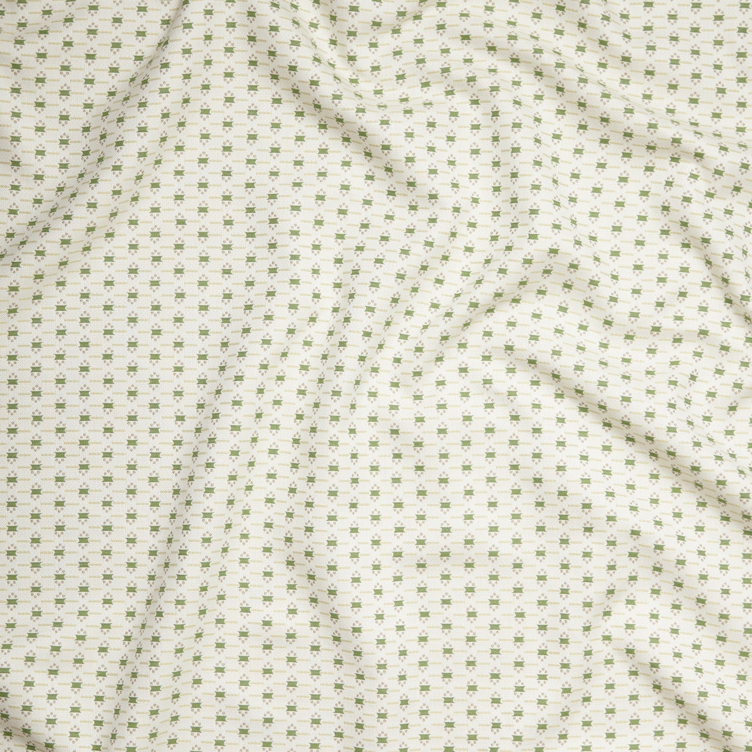 Close up of gently draped woven Indoor-Outdoor fabric with small scale geometric ditsy print in green and tan on white. 