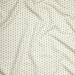 Close up of gently draped woven Indoor-Outdoor fabric with small scale geometric ditsy print in green and tan on white. 