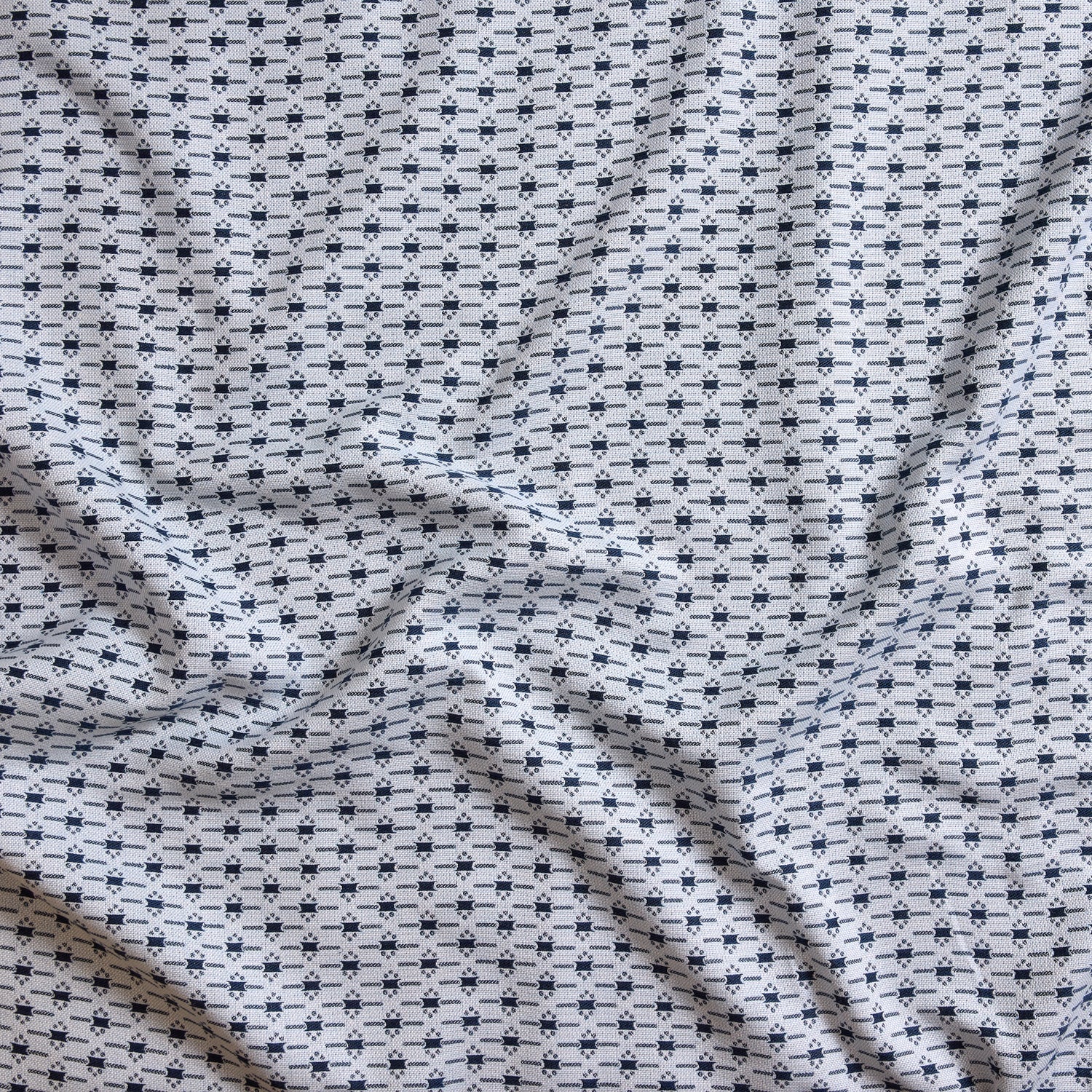 Close up of gently draped woven Indoor-Outdoor fabric with small scale geometric ditsy print in navy and slate blue on white. 