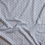 Close up of gently draped woven Indoor-Outdoor fabric with small scale geometric ditsy print in navy and slate blue on white. 