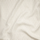 Close up of gently draped woven Indoor-Outdoor fabric with small scale geometric ditsy print in beige and taupe on ivory. 