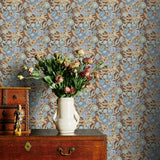 Blue and Brown floral wallpaper with a vase of flowers on a wooden dresser