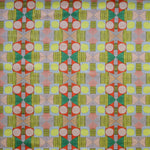Close up of printed fabric with a complex geometric pattern with pink, red, light purple, green and yellow. 