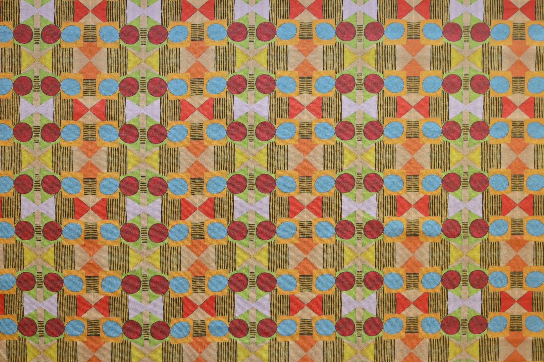Close up of printed fabric with a complex geometric pattern with red, blue, orange and green. 