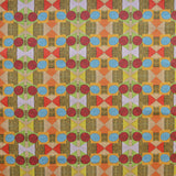 Close up of printed fabric with a complex geometric pattern with red, blue, orange and green. 