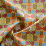 Close up of gently draped printed fabric with a complex geometric pattern with red, blue, orange and green. 