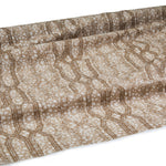 Draped fabric coming off a roll with monochomatic geometric stripe and mottled textural background in shades of  brown.