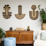 Living room scene with three black and tan sculptural woven panels, ornately carved wooden chest, baskets with house plans, white upholstered side chair and a stripe patterned footstool in blue.