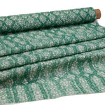 Draped fabric coming off a roll with monochomatic geometric stripe and mottled textural background in shades of green.