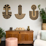 Living room scene with three black and tan sculptural woven panels, ornately carved wooden chest, baskets with house plans, white upholstered side chair and a stripe patterned footstool in orange. 