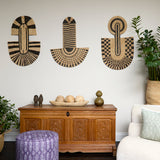 Living room scene with three black and tan sculptural woven panels, ornately carved wooden chest, baskets with house plans, white upholstered side chair and a stripe patterned footstool in purple.