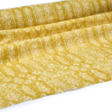 Draped fabric coming off a roll with monochomatic geometric stripe and mottled textural background in shades of yellow.