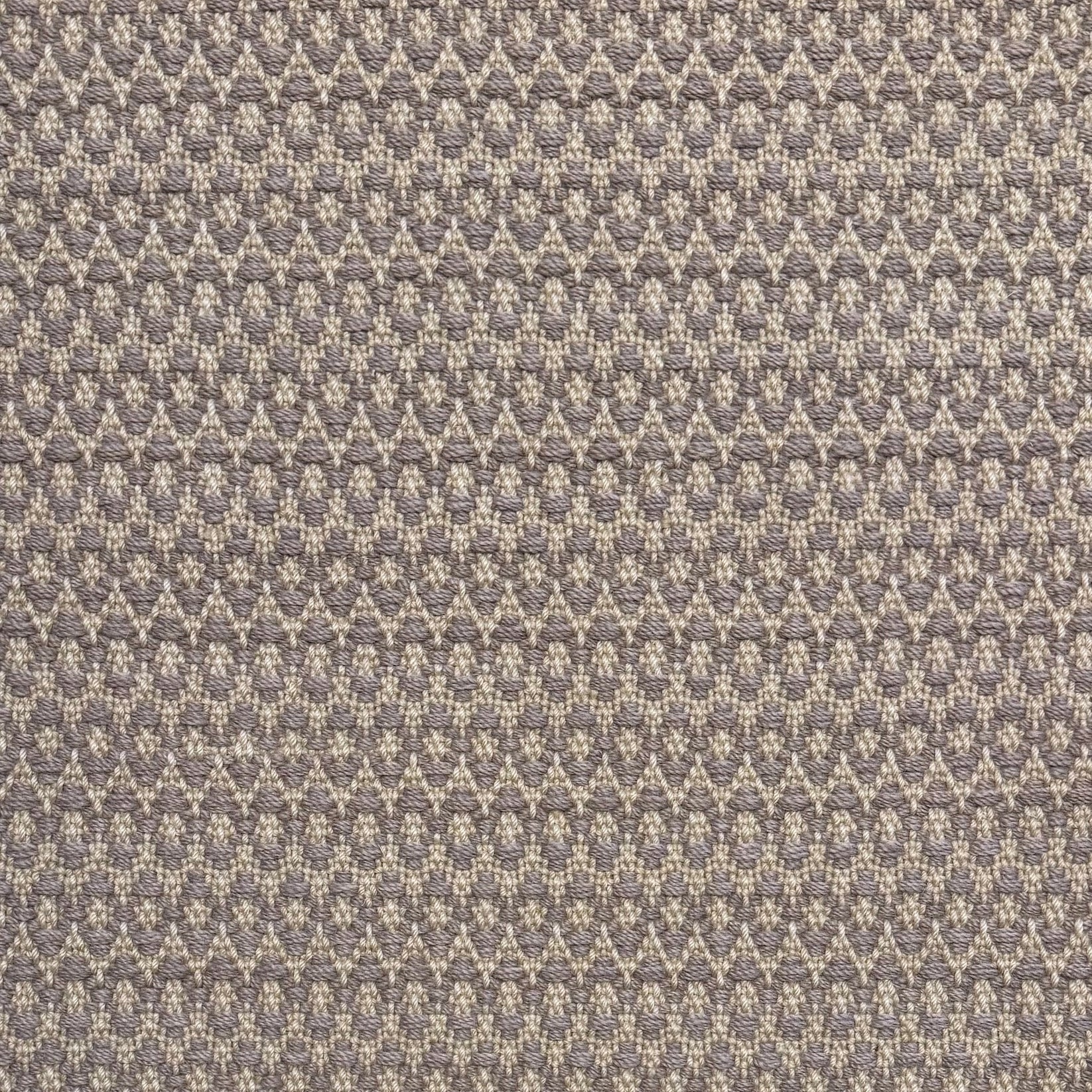 Handwoven wool rug with textural oval pattern in grey on a beige field. 