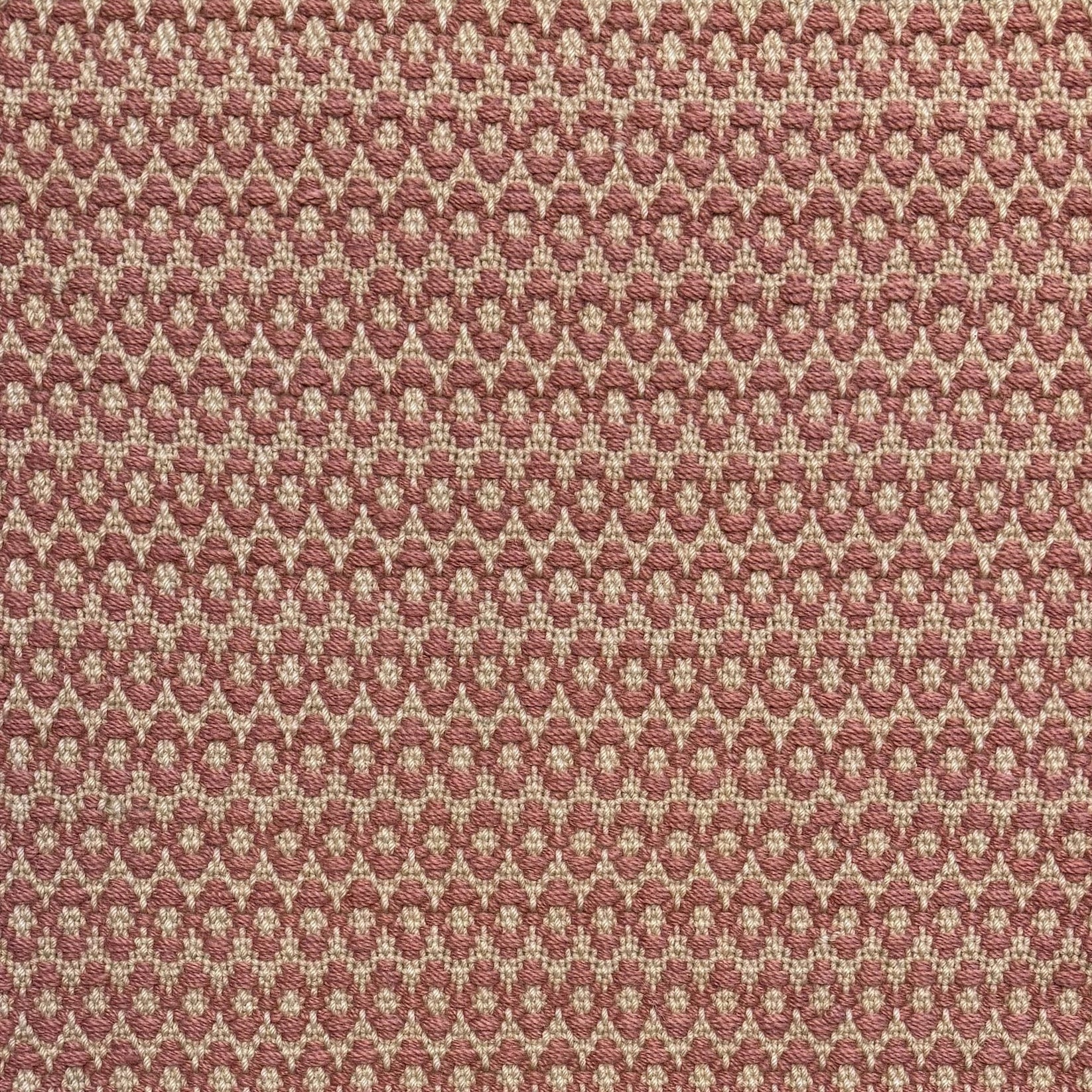 Handwoven wool rug with textural oval pattern in blush pink on a beige field. 