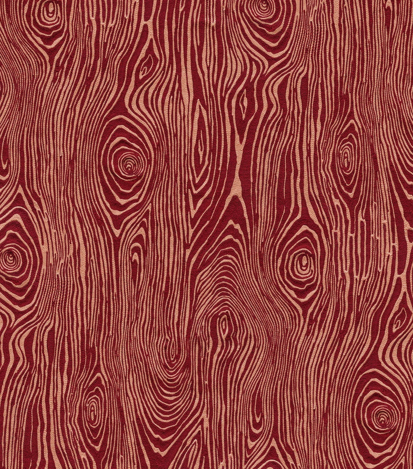Detail of fabric in a textural wood grain print in coral on a red field.