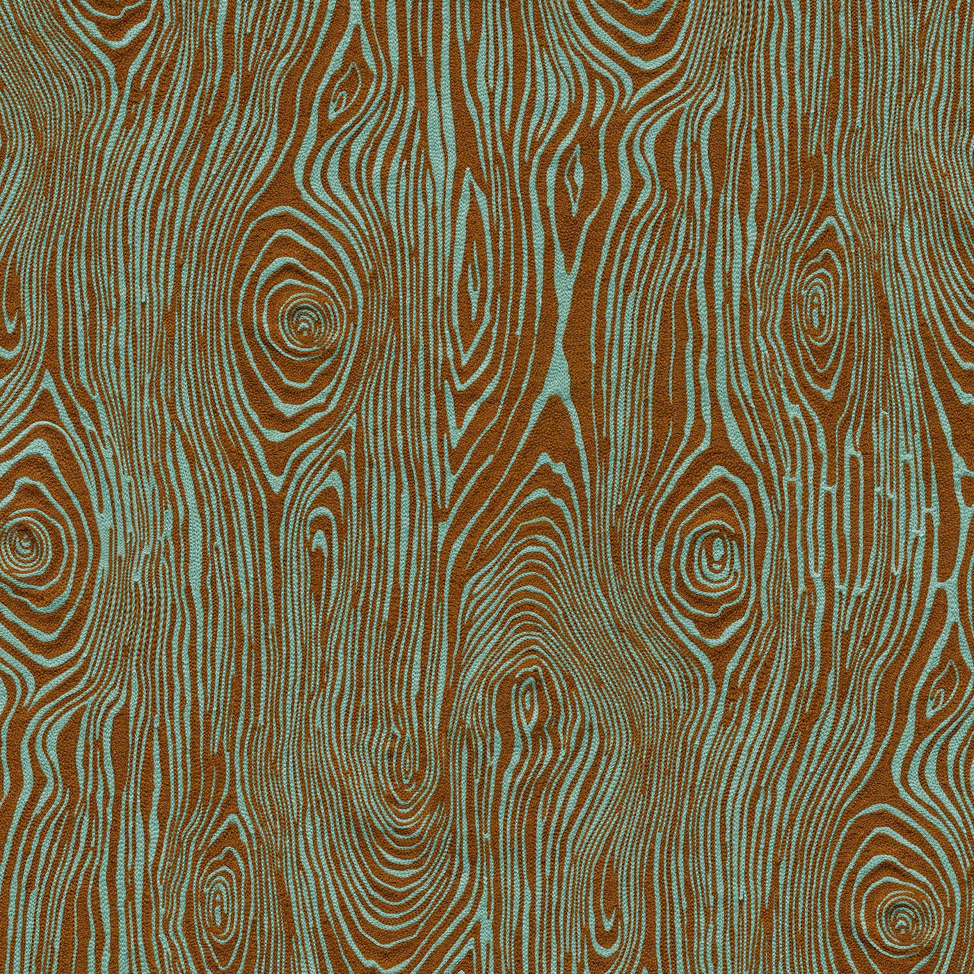 Detail of fabric in a textural wood grain print in brown on a turquoise field.