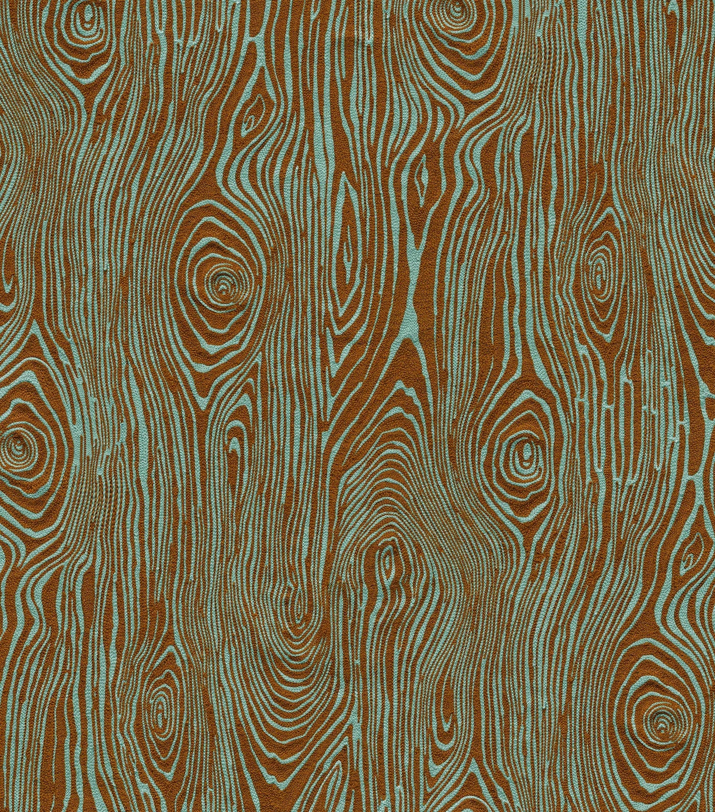 Detail of fabric in a textural wood grain print in brown on a turquoise field.