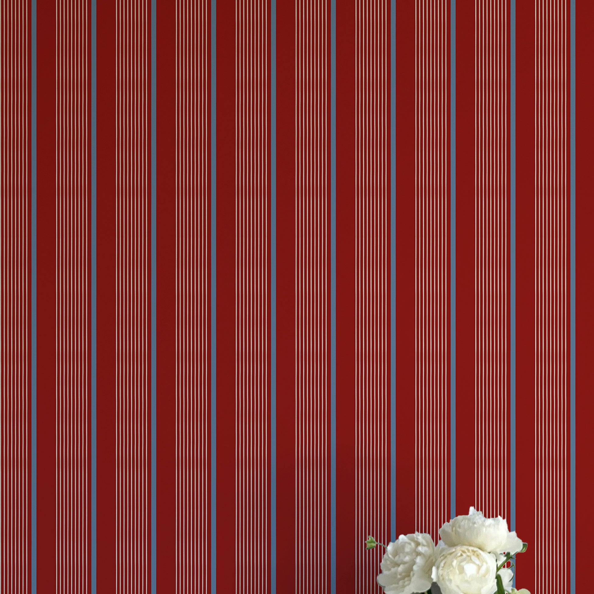 Striped red and blue wallpaper with a vase of flowers on a matching surface.