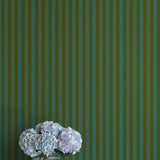 Striped green wallpaper with a vase of flowers in the foreground
