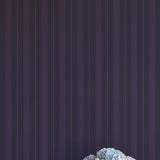 Vase of flowers on a white surface with a dark purple striped wallpaper background