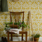 Wooden chair with a basket of flowers against a yellow patterned wall.