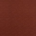 Detail of fabric in a minimalist wood grain print in tan on a rust field.