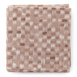 A stack of fabric swatches in a painterly checked pattern in shades of pink.