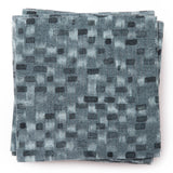 A stack of fabric swatches in a painterly checked pattern in shades of blue and navy.