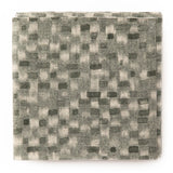 A stack of fabric swatches in a painterly checked pattern in shades of olive.