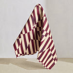 Draped fabric in a trompe l'oeil stripe pattern with geometric shapes in cream and burgundy. 