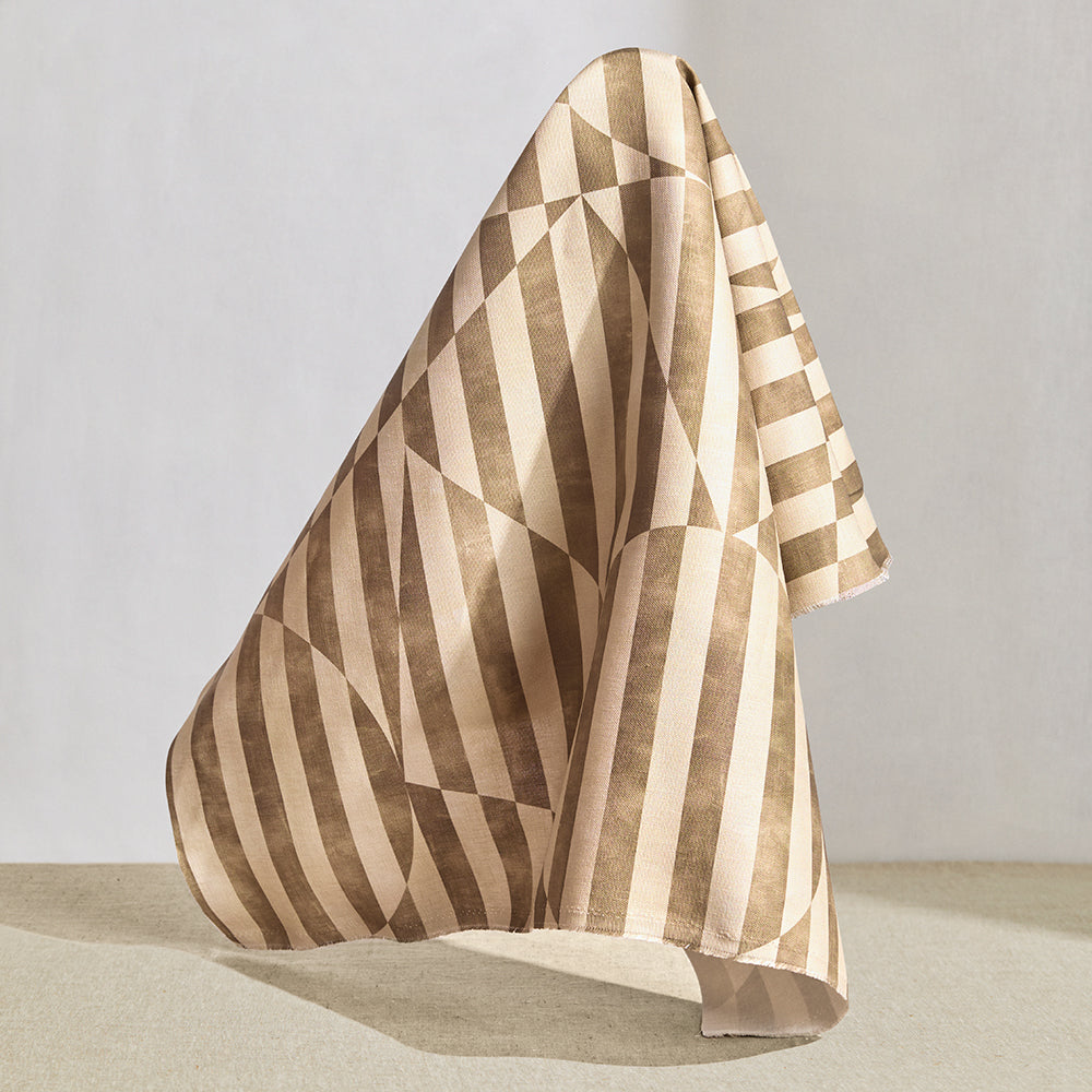 Draped fabric in a trompe l'oeil stripe pattern with geometric shapes in cream and taupe.