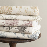 Wooden side table with stacks of folded fabric in floral design in various colors. 