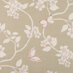 Detail of fabric in a flower and butterfly print in cream and pink on a tan field.