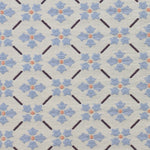 Detail of fabric in a repeating floral lattice print in blue, coral and black on a cream field.