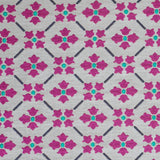Detail of fabric in a repeating floral lattice print in magenta and turquoise on a greige field.