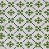 Detail of fabric in a repeating floral lattice print in shades of green on a white field.