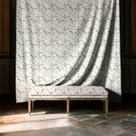 Decorative bench with floral pattern in front of a curtain with similar design