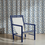 Blue chair in front of a blue floral patterned curtain