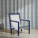 Blue chair in front of a blue floral patterned curtain