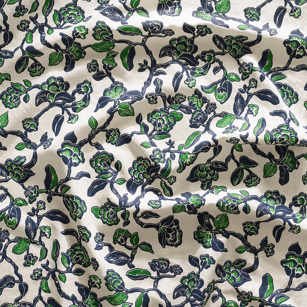 Close up of gently draped printed linen in a hand drawn branch and flower design in navy blue and green on white. 