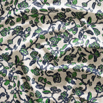 Close up of gently draped printed linen in a hand drawn branch and flower design in navy blue and green on white. 