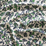 Close up of gently draped printed linen in a hand drawn branch and flower design in navy blue and green on white. 