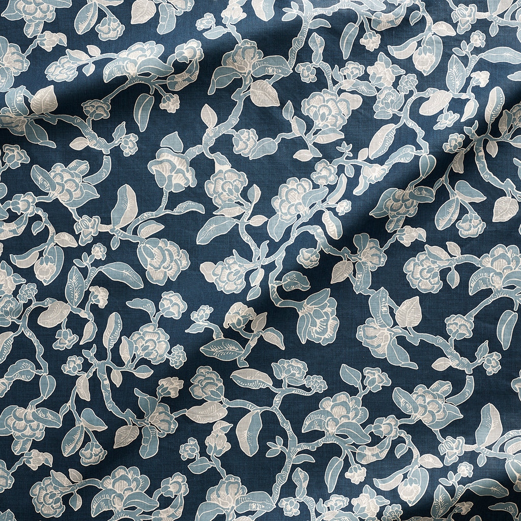 Close up of gently draped printed linen in a hand drawn branch and flower design in light blue and white on navy blue.