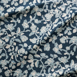 Close up of gently draped printed linen in a hand drawn branch and flower design in light blue and white on navy blue.
