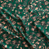 Close up of gently draped printed linen in a hand drawn branch and flower design in black and light pink on emerald green.
