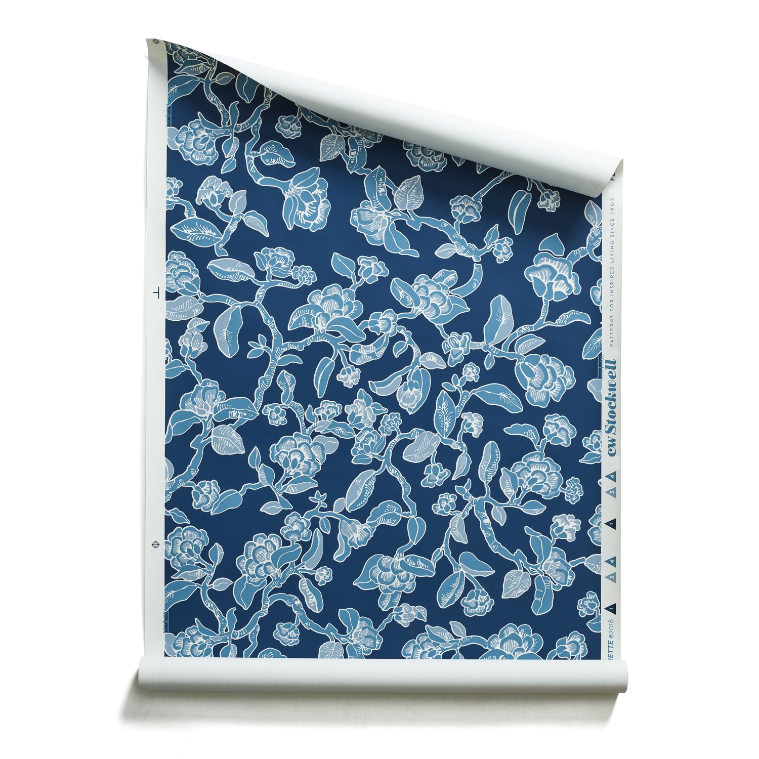 Roll of wallpaper in a hand drawn branch and flower design in shades of blue on navy.