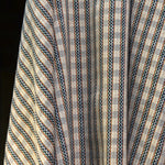 Handwoven fabric gently draped in a tight checkerboard pattern with blue, green yellow and red stripes against a cream field.