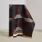 Wallpaper roll in a graphic geometric design in burn siena, black, taupe and cream.