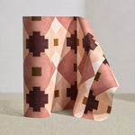 Wallpaper roll in a bold abstract checkerboard pattern in blush, oxblood, camel and cream.