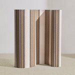 Wallpaper roll in a complex geometric stripe in brown, tan, taupe and black on a cream field.